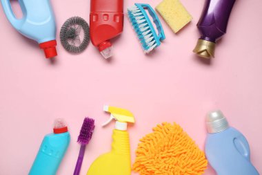 Farklı deterjanlar ve pembe arka planda temizlik malzemeleriyle kompozisyon