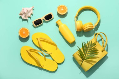 Turkuaz arka planda turuncu, kulaklık ve plaj aksesuarlarıyla yaz kompozisyonu