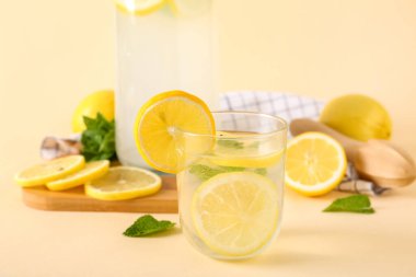 Bej arka planda naneli bir bardak ve bir şişe taze limonata.