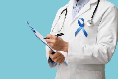 Dosya tahtası ve mavi kurdeleli bir erkek doktor. Prostat kanseri farkındalığı