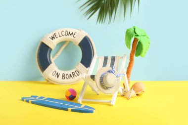 Sörf tahtası, deniz kabukları, can simidi halkası ve renkli arka planda plastikten yapılmış palmiye ağacı olan mini iskemle.