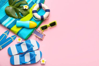 Pembe arka planda güneş kremi ve plaj aksesuarları olan kompozisyon
