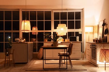 Mutfağın içinde tezgahlar, yemek masası ve geceleri parlayan lambalar var.