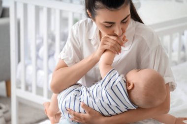 Güzel, genç, mutlu bir anne ve tatlı küçük kızı evde yatakta oturuyor.