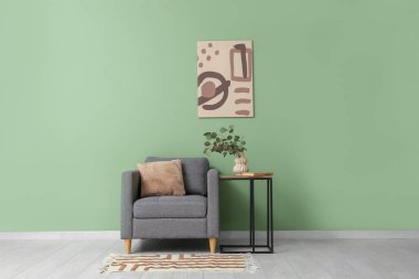Koltuk, masa ve vazo içinde okaliptüs dalları ile yeşil duvarın yanında oda içi