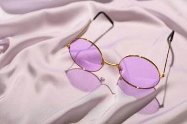 Açık renk kumaş arka planda leylak güneş gözlüğü