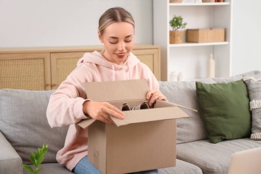 Genç bir kadın evdeki kanepede spor ayakkabı kutusundan ayakkabı alıyor.