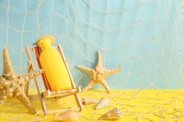 Renkli arka planda güneş kremi, deniz yıldızı ve deniz kabukları olan mini iskemle.