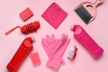 Farklı temizlik malzemeleriyle kompozisyon ve pembe arka planda bir şişe deterjan.