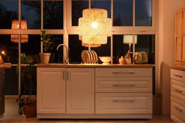 Akşamları tezgah ve parlayan lambayla modern mutfağın içinde.