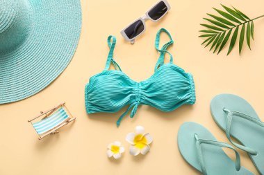 Bej arka planda mayolu, çiçekli ve plaj aksesuarlı kompozisyon