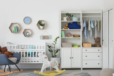 Bebek beşiği, dolabı ve sallanan koltuğu olan bir kreş.