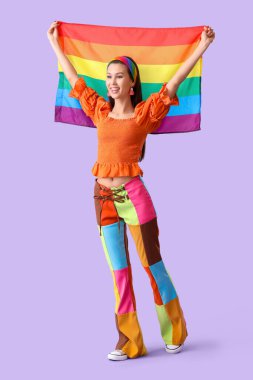Beautiful young woman with LGBT flag on lilac background