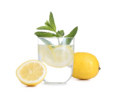 Bir bardak lezzetli limonata, taze limonlar ve beyaz arka planda nane şekeri.