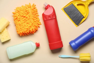 Renkli arka planda deterjan şişeleri ve farklı temizlik malzemeleriyle kompozisyon