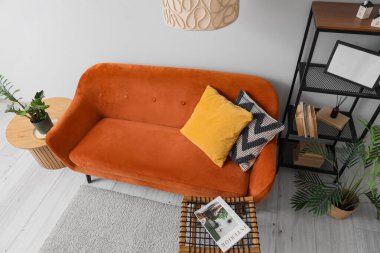 Rahat kahverengi kanepe, raf ünitesi ve oturma odasındaki beyaz duvarın yanındaki masa.