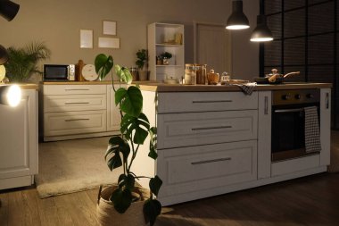 Geceleri beyaz tezgahlı ve parlayan lambalı mutfağın içi.