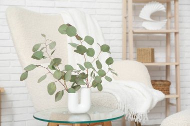 Oturma odasının içinde okaliptüs dalları olan masa ve vazo, yakın plan.