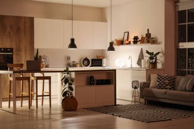 Geceleri tezgahları, masa lambaları ve parlayan lambaları olan modern mutfağın içi.