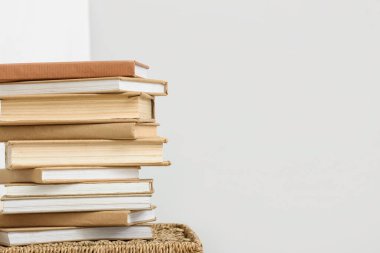 Hasır sepetin üzerinde beyaz duvarın yanında kitap yığını
