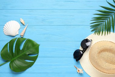 Şık güneş gözlüklü kompozisyon, hasır şapka, palmiye yaprakları ve ahşap arka planda deniz kabukları