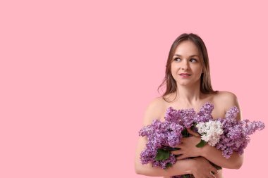 Pembe arka planda çiçek açan güzel genç bir kadın.