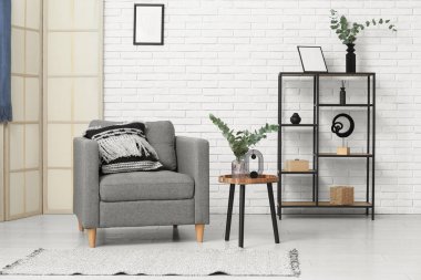 Gri koltuklu ve kahve masasında okaliptüs dalları olan şık bir oda.