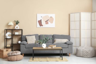 Oturma odasının içinde okaliptüs dalları olan kanepe, masa ve vazolar.