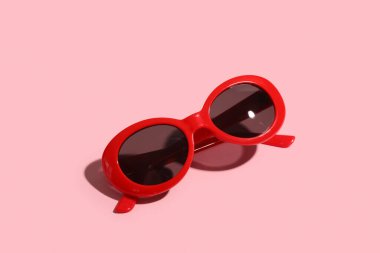 Pembe arka planda şık kırmızı güneş gözlükleri