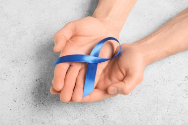 Gri grunge arka planda mavi kurdeleli erkek eller. Prostat kanseri farkındalığı