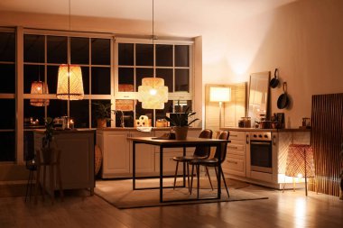 Mutfağın içinde tezgahlar, yemek masası ve geceleri parlayan lambalar var.