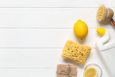 Beyaz ahşap arka planda temizlik, fırça ve sünger için doğal ürünlerle kompozisyon