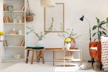 Kitap rafı, nergisleri ve çiçek açan vazolarla aydınlık oturma odasının içinde.