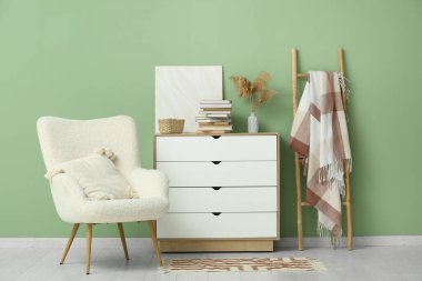 Beyaz koltuklu şık bir oturma odası, şifoniyer ve merdiven üzerine kitap yığını.