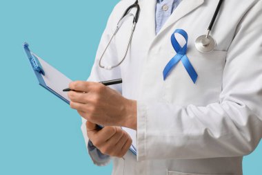 Dosya tahtası ve mavi kurdeleli bir erkek doktor. Prostat kanseri farkındalığı