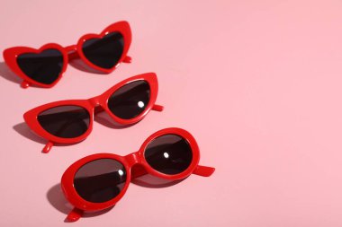 Pembe arka planda farklı kırmızı güneş gözlükleri.