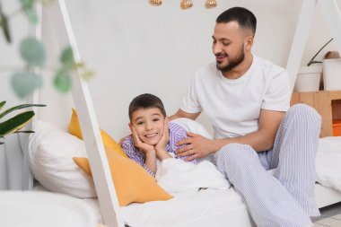 Mutlu bir baba ve oğlu evde pijamalarıyla yatıyorlar.