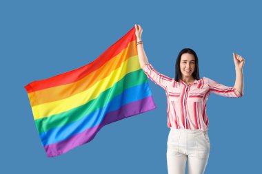 Beautiful young woman with LGBT flag on blue background