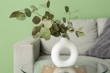 Oturma odasının iç tarafındaki masada okaliptüs dalları olan vazo, yakın plan.