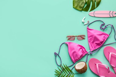 Turkuaz arka planda mayo, hindistan cevizi ve plaj aksesuarlarıyla yaz kompozisyonu