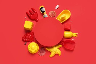 Boş kağıt çarşaf, plaj kumları ve kırmızı arka plandaki çocuklar için plaj aksesuarlarından yapılmış çerçeve.