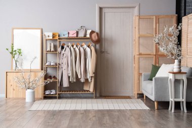 Koridorun içinde kanepe, elbise askılığı, büyük çerçeve ve vazolarda açan güzel dallar var.