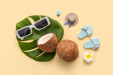 Hindistan cevizi, tropikal yaprak ve bej arka planda dekoratif plaj aksesuarları.