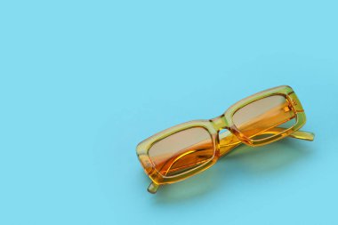 Mavi arkaplanda şık sarı güneş gözlükleri