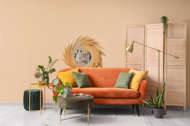 Rahat kahverengi kanepe, ev bitkileri ve oturma odasının iç tarafında katlanan ekran.