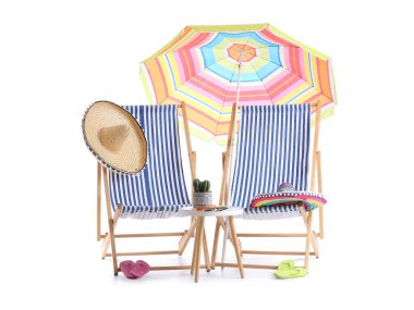 Renkli plaj şemsiyeli çizgili güverte sandalyeleri ve beyaz arka planda izole edilmiş seyahat aksesuarları.