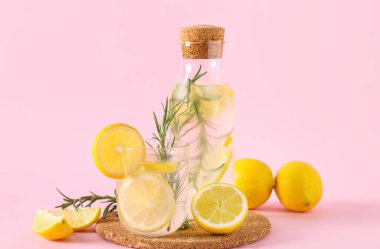 Pembe arka planda biberiyeli bir şişe taze limonata.