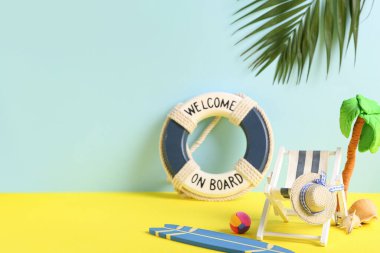 Sörf tahtası, deniz kabukları, can simidi halkası ve renkli arka planda plastikten yapılmış palmiye ağacı olan mini iskemle.