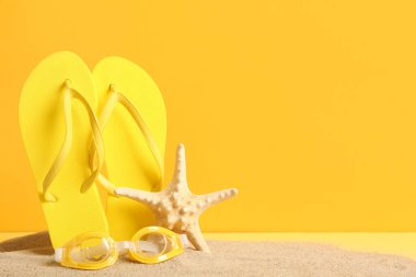 Yüzme gözlüklü terlikler ve turuncu arka planda deniz yıldızı.