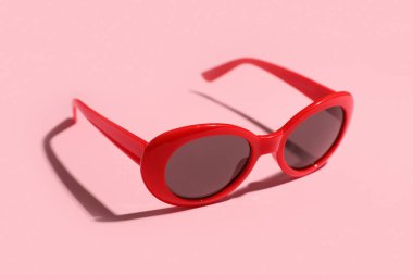 Pembe arka planda şık kırmızı güneş gözlükleri